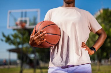 Basketbol oynayan genç bayana yakın çekim. Güneşli bir günde pratik yapıyor..