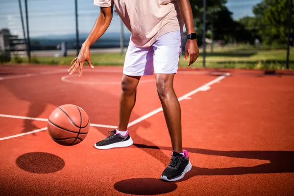 Genç siyahi kadın sabahları spor salonunda tek başına basketbol oynuyor. O, topu sürüyor..