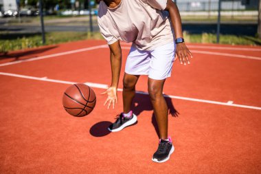 Genç siyahi kadın sabahları spor salonunda tek başına basketbol oynuyor. O, topu sürüyor..