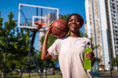 Genç siyahi kadın sabahları spor salonunda tek başına basketbol oynuyor. İçecek ve balo hazırlıyor..