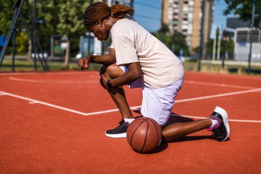 Genç bir kadın sabah spor salonunda tek başına basketbol oynuyor. Dizinde ağrı var..
