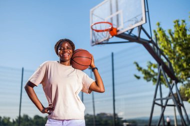 Genç bir kadın sabah spor salonunda tek başına basketbol oynuyor. Mutlu kız güneşli bir günde basketbol oynuyor..