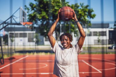 Genç bir kadın sabah spor salonunda tek başına basketbol oynuyor. Mutlu kız güneşli bir günde basketbol oynamaya hazır..