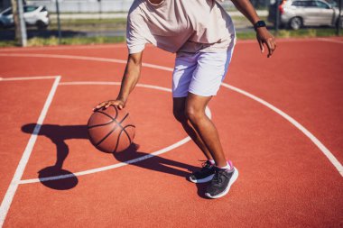 Genç siyahi kadın sabahları spor salonunda tek başına basketbol oynuyor. O, topu sürüyor..