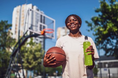 Genç siyahi kadın sabahları spor salonunda tek başına basketbol oynuyor. İçecek ve balo hazırlıyor..