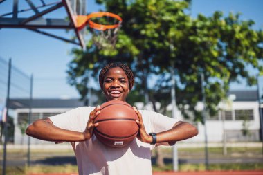 Genç bir kadın sabah spor salonunda tek başına basketbol oynuyor. Mutlu kız güneşli bir günde basketbol oynuyor..
