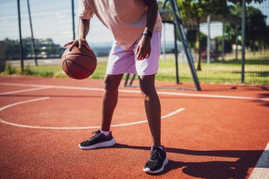 Genç siyahi kadın sabahları spor salonunda tek başına basketbol oynuyor. O, topu sürüyor..