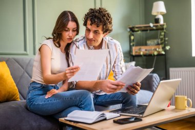 Çift faturaları kontrol ederken ev ekonomisini tartışıyor. Mali belgeleri kontrol ediyorlar ve oturma odasındaki aile bütçesini hesaplıyorlar..