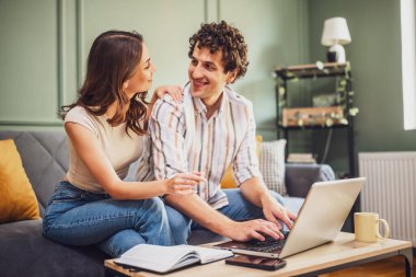 Çift dizüstü bilgisayarda ev finansmanını tartışıyor ve oturma odasında aile bütçesini hesaplıyor..