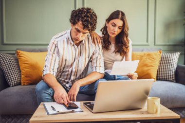 Çift faturaları kontrol ederken ev ekonomisini tartışıyor. Mali belgeleri kontrol ediyorlar ve oturma odasındaki aile bütçesini hesaplıyorlar..