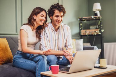 Bir karı koca laptoplarında neşeli bir konuşma yapıyor, kahkahalarını paylaşıyor ve evlerinin rahatlığından internet üzerinden bağlanıyorlar..