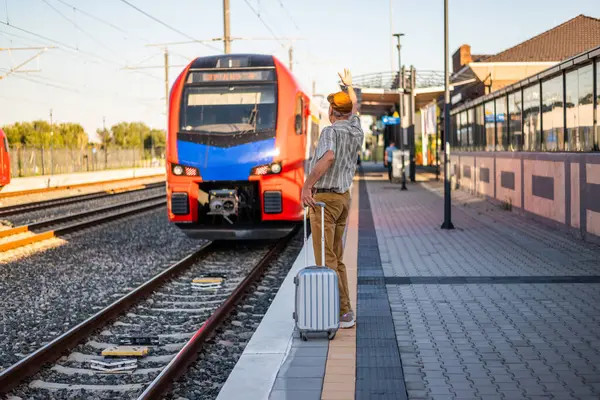 Senior man is standing at railway station. He missed the train departure. Senior people traveling.