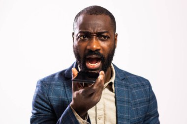 Close up portrait of angry African-american businessman who is talking on mobile phone and threatens.