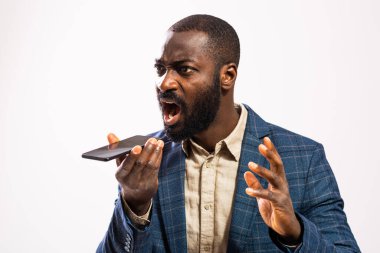 Close up portrait of angry African-american businessman who is talking on mobile phone and threatens.