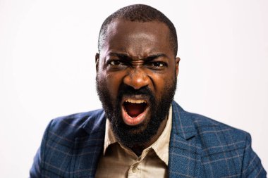Close up portrait of angry African-american businessman who is looking at camera and shouting.