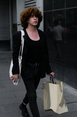 non-binary person walk with screen bag ad after shopping