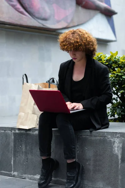 Non-binary person working at the laptop typing and searching some ecommerce. Non-binary person working at the laptop typing and searching some e-commerce