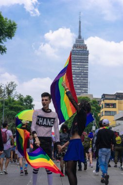 Mexico City, 25 Haziran 2022 katılımcılar gay yürüyüşünün dönüşünde el ele tutuşup lgbt bayrağı sallıyorlar. Arkadan dikey biçimde çekilen