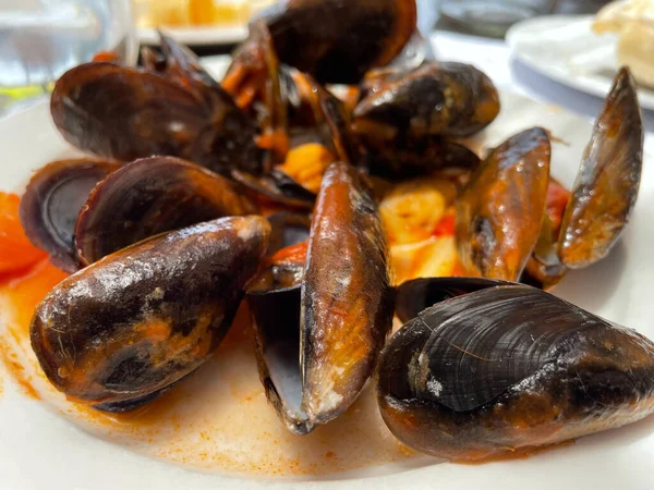 mussels cooked in sauce on a white plate, Spanish tapa in a restaurant
