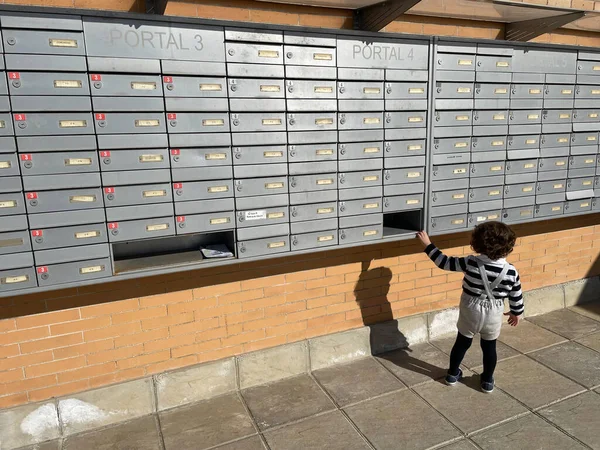 Child looking at a group of mailboxes in a residential complex