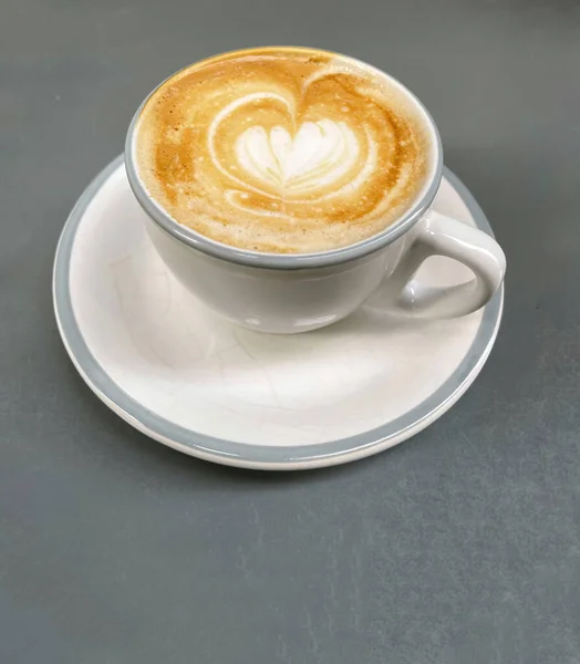 Gri arka planda kalp şeklinde köpük olan espresso bardağının üst görüntüsü
