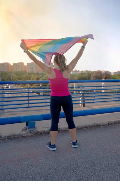 Lgtbi gurur bayrağı taşıyan genç bir kadın arka planda daireleri olan bir köprüde hakları için savaşıyor. Kabullenme lgtbi, gay, lezbiyen, gurur günü.