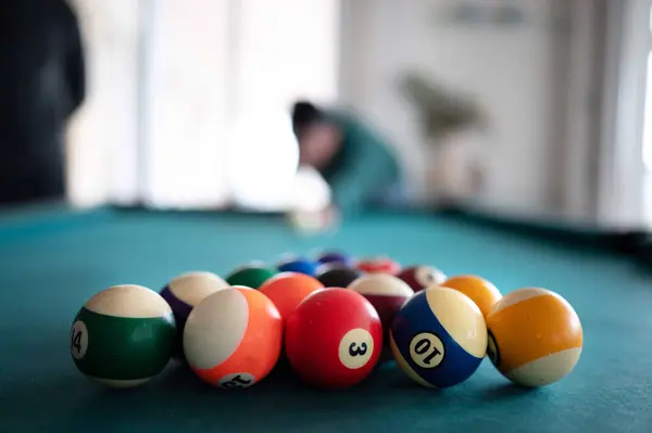 Pool table with shiny balls, in the background player ready to shoot. Focus Selective