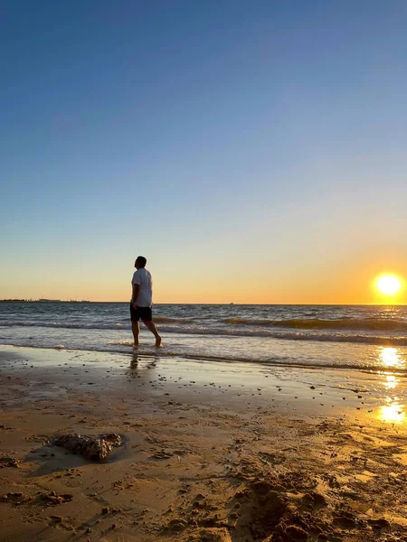 Gün batımında sahilde yürüyen bir adam. Tatil kavramı