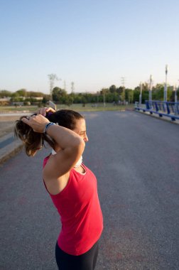 Genç aktif sporcu kadın koşudan ve koşudan sonra saçını geriye doğru çekerek ara veriyor. Dikey