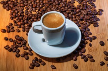 Kahve bardağı ve kahve çekirdekleri ağaçta yatıyor.