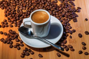 Kahve bardağı ve kahve çekirdekleri ağaçta yatıyor.