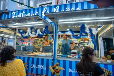 Lizbon, Portekiz. 22 Haziran 2024. Lizbon 'daki Santo Antonio şenliklerinde churros kervanı, renkli sokak yemekleri satan churros ve tatlılar, şenlik ortamında müşteriler ve satıcılar..