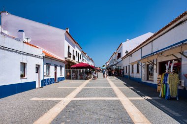 Alentejo Portekiz. 04 Ağustos 2024. Porto Covo Alentejo Portekiz 'de, Charming kaldırım taşı caddesi bir Portekiz köyünde evleri, dükkanları ve kafeleri beyazlatılmış..