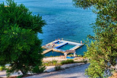 Santa Clara barajının berrak mavi suları, çevreleyen tepeleri ve parlak gökyüzünün altındaki yemyeşil yeşil manzarası, Alentejo Portekiz 'deki Santa Clara barajı.