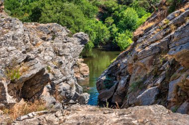 Bereketli yeşillik ve kayalık arazi ile çevrili sakin bir nehir, doğa ve seyahat kavramları için mükemmel, Pego das Pias Alentejo Portekiz 'de güzel bir arazi.