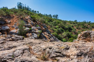 Bereketli yeşillik ve kayalık arazi ile çevrili sakin bir nehir, doğa ve seyahat kavramları için mükemmel, Pego das Pias Alentejo Portekiz 'de güzel bir arazi.