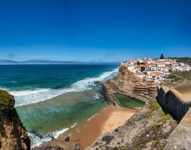 Sintra, Portekiz. 24 Ağustos 2024 'te okyanusa bakan bir uçurumun kenarındaki sahil köyünde, aşağıdaki kumlu plaja dalgalar vururken, Azenhas, Sintra, Portekiz' de Mar yapar..