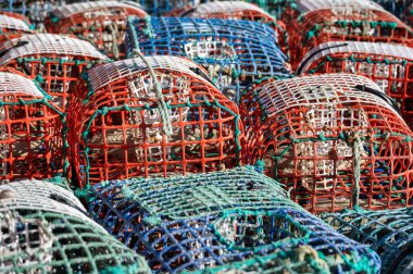 Colorful fishing traps stacked together in a sunny harbor, showcasing traditional fishing equipment. clipart