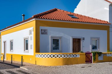 Ericeira, Portugal. 21 December 2024 Traditional house in Ericeira village in Portugal. Charming traditional Portuguese house with vibrant yellow and white facade under a clear blue sky.