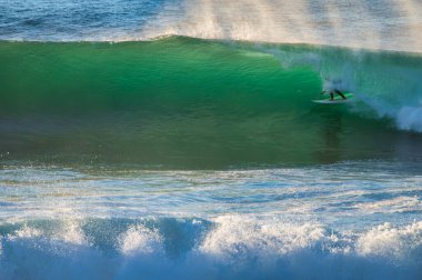 Ericeira, Portekiz. 25 Aralık 2024. Portekiz, Ericeira 'da Coxos' ta sörf yapan bir sörfçü. Güçlü bir dalgada sörf yapan bir sörfçü. Altından bir sprey ve arkasında okyanusla..