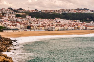  Ünlü Nazare Deniz Feneri 'nden çekilen Portekiz' in Nazar kasabasının çarpıcı panoramik görüntüsü. Görüntü güzel Praia da Nazar 'ı gözler önüne seriyor. Uçsuz bucaksız altın kumu ve mavi-yeşil tonlarında Atlantik Okyanusu.. 