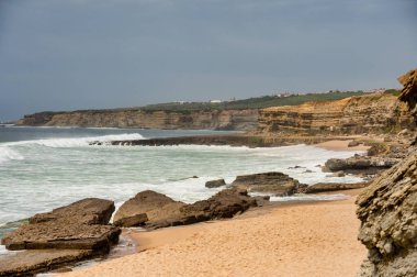 Portekiz 'in Ericeira kentindeki Pedra Branca sahilinde sörf ve doğal güzelliklerle bilinen vahşi Atlantik dalgaları çarpışıyor..