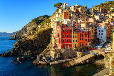 Stunning view of Riomaggiore village in Cinque Terre National Park, beautiful cityscape with colorful houses and green terraces on cliffs over a sea, Liguria region of Italy. Outdoor travel background