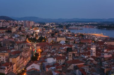 Alacakaranlıktaki St Michaels kale duvarından Sibenik 'in üst görüntüsü, Hırvatistan' ın Dalmaçya kıyısındaki Adriyatik kıyısında tarihi bir şehir, rahat evleri ve Krka nehri olan manzaralı şehir manzarası, dış seyahat geçmişi