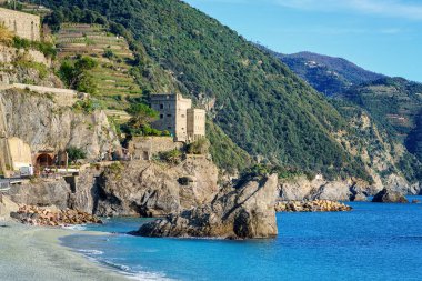 Monterosso al Mare in Cinque Terre Ulusal Parkı 'nın ortaçağ taştan kalesi Down Tower, yeşil tepeler ve İtalya' nın Liguria bölgesindeki kayalıklar manzaralı manzarası. Dış seyahat arka planı