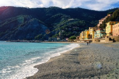Monterosso al Mare rıhtımının manzarası Cinque Terre Ulusal Parkı, renkli evleri olan güzel şehir manzarası, deniz üzerindeki yeşil tepeler ve uçurumlar, Liguria bölgesi, İtalya. Dış seyahat arka planı