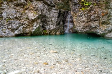 Pisnica nehrinin kristal berrak turkuaz renkli suyu ve küçük şelale, Slovenya, Triglav Ulusal Parkı. Dış seyahat arka planı