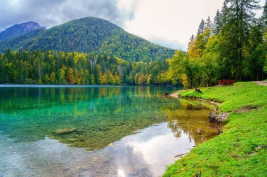 Laghi di Fusine aşağı göl, Tarvisio, İtalya. İnanılmaz sonbahar manzarası, yansımalı kristal berrak su ve renkli orman Mangart sıradağlarıyla çevrili, dış dünya seyahati arka planı.