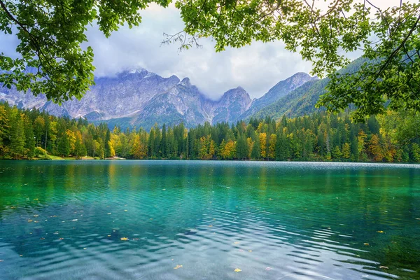 Laghi di Fusine aşağı göl, Tarvisio, İtalya. İnanılmaz sonbahar manzarası, yansımalı kristal berrak su ve renkli orman Mangart sıradağlarıyla çevrili, dış dünya seyahati arka planı.