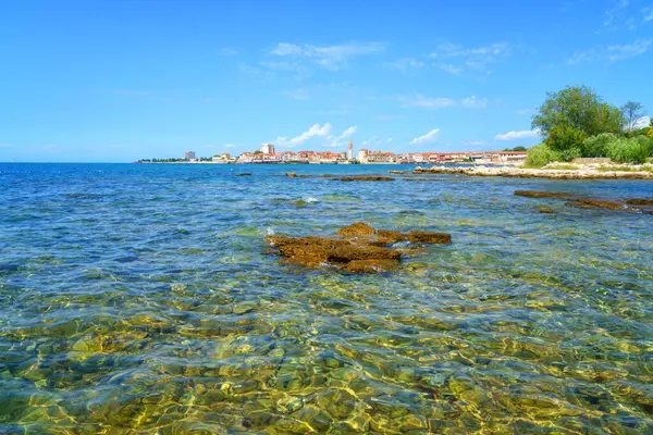 Hırvatistan 'ın Istria kentindeki Adriyatik kıyısındaki Umag eski kentinin manzarası. Ortaçağ mimarisi ile yaz manzarası, berrak mavi deniz suyu ve bulutlu gökyüzü, dış seyahat arka planı